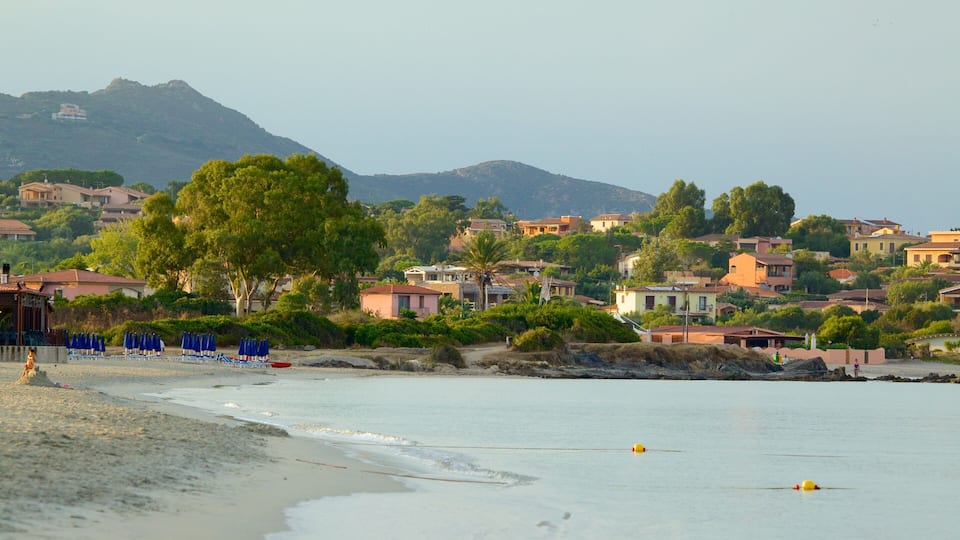 A coastal town with a beach, blue umbrellas, and houses.
