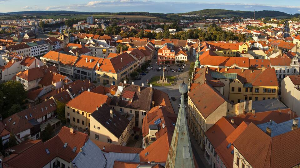A panoramic view of a historic town with red-tiled roofs and a mix of traditional and modern architecture.