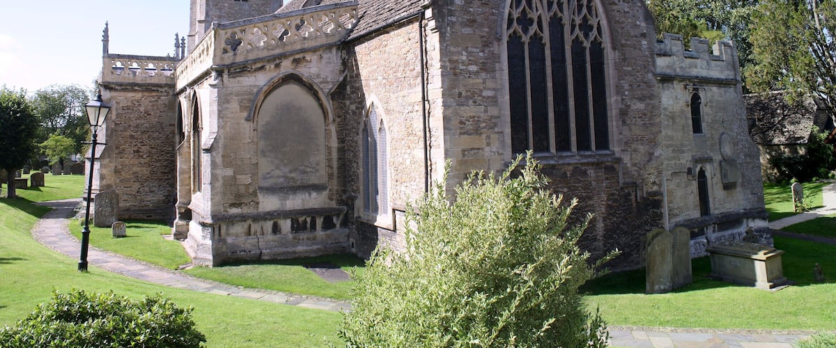A historic church with a pointed roof, a clock tower, and a large arched window.