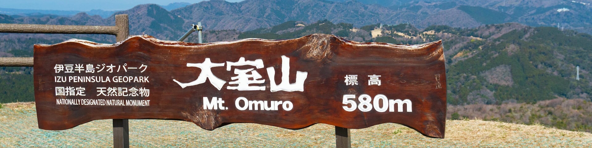 A wooden sign with Japanese text indicating Mt. Omuro at 580m, with a view of mountains in the background.
