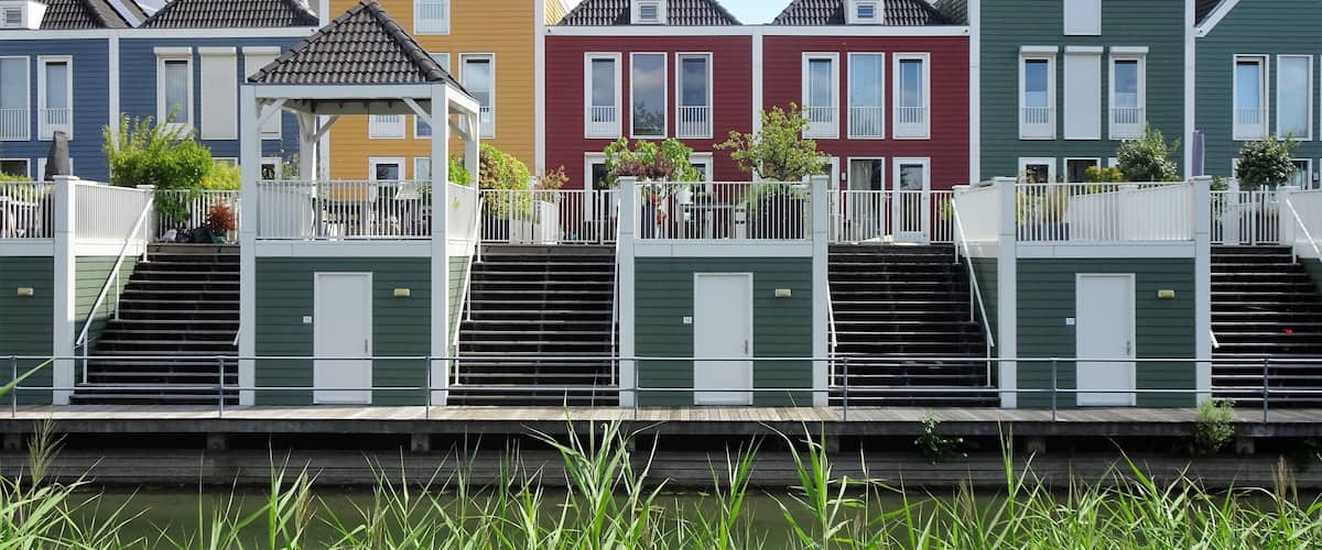 Une rangée de maisons aux couleurs vives, avec un canal au premier plan.