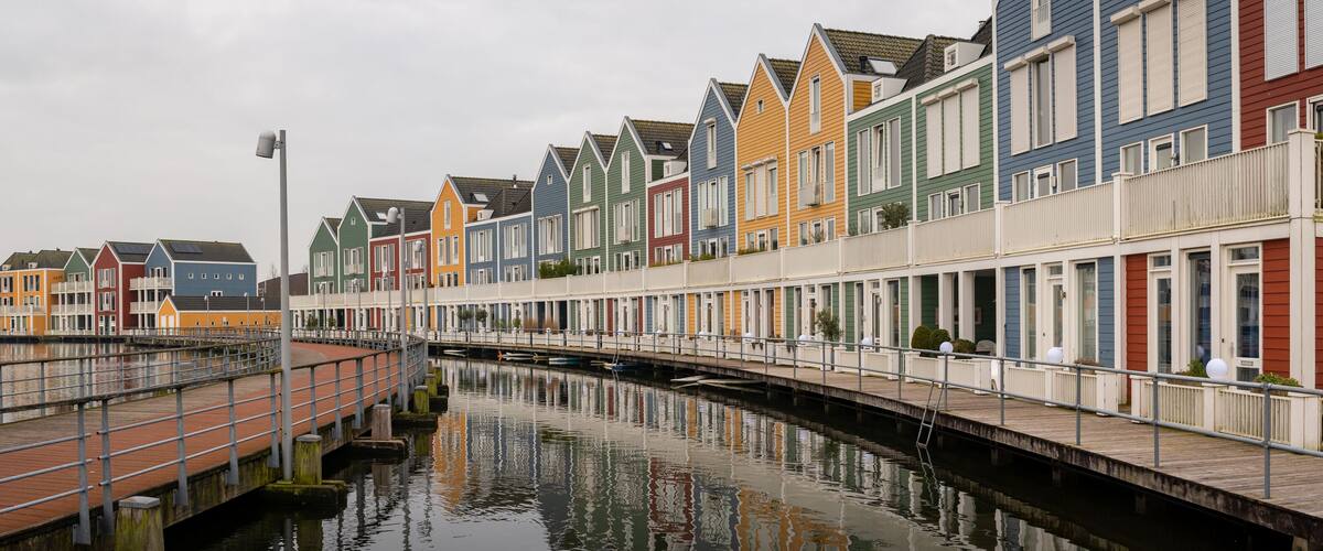 A canal with colorful row houses on one side and a bridge crossing over it.