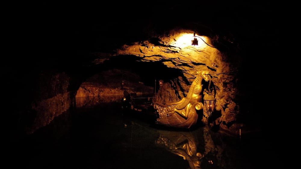 Une grotte abritant une statue dorée et une lanterne.