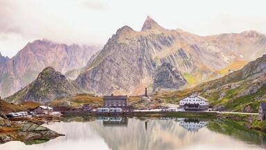 A mountainous landscape with a lake, a church, and several buildings.