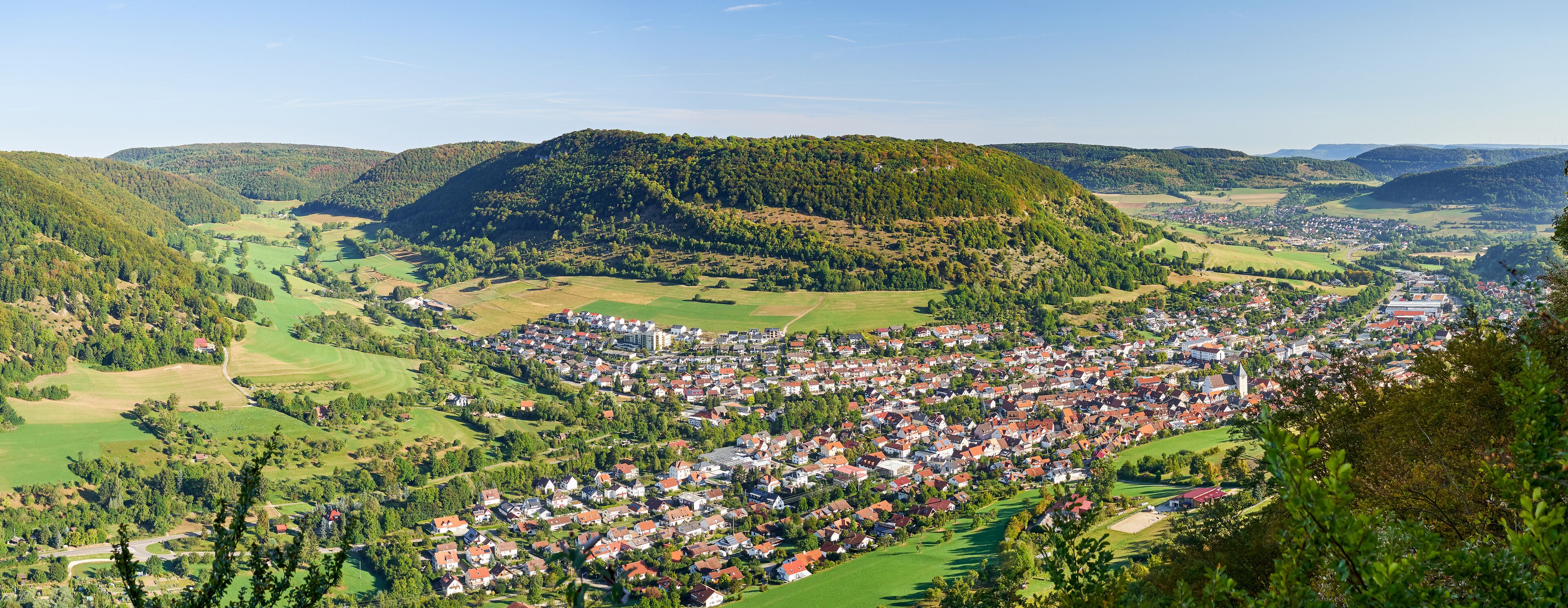 A town nestled in a valley surrounded by hills and forests.
