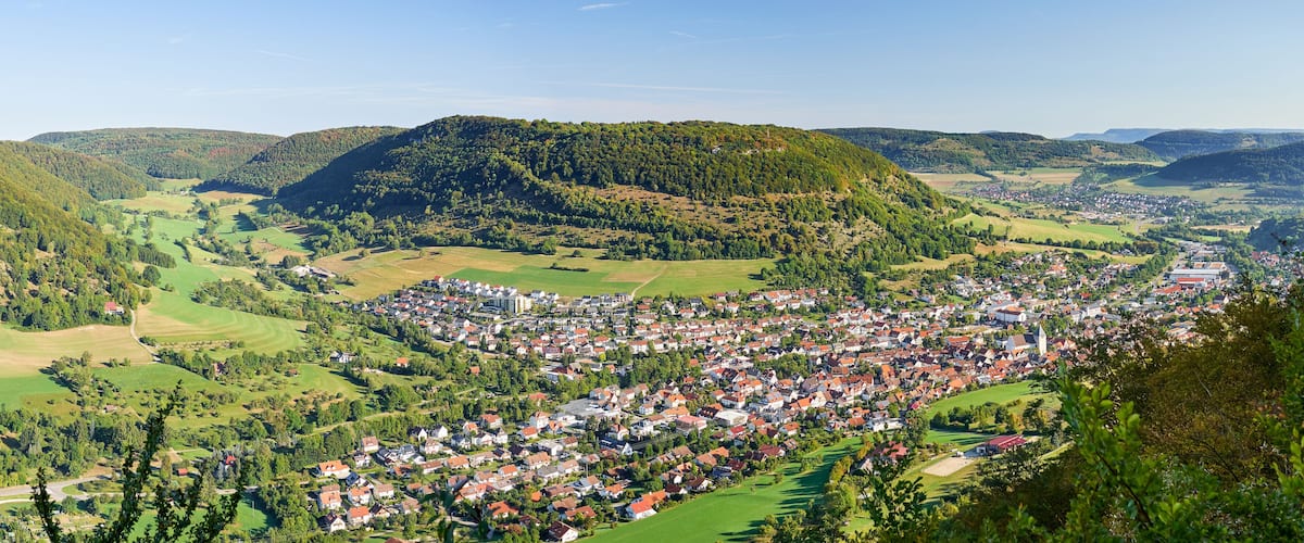 A town nestled in a valley surrounded by hills and forests.