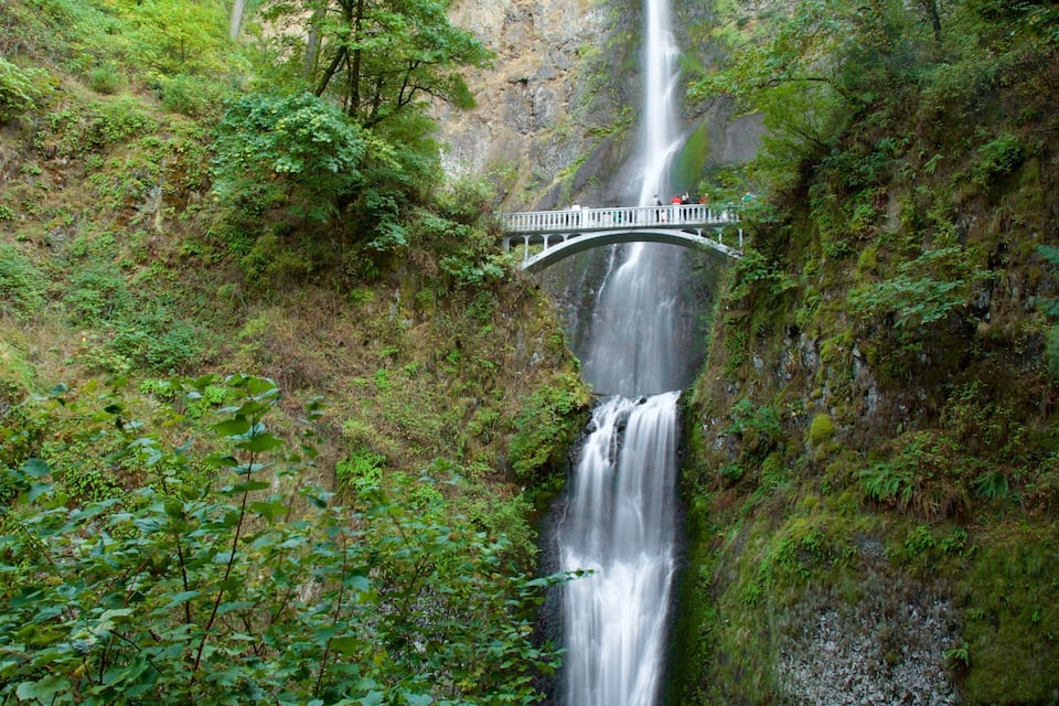 A waterfall cascading down a rocky cliff, with a bridge spanning across the water.