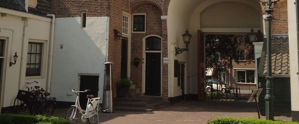 A traditional brick building with a white facade, a central archway, and a bicycle parked in front.