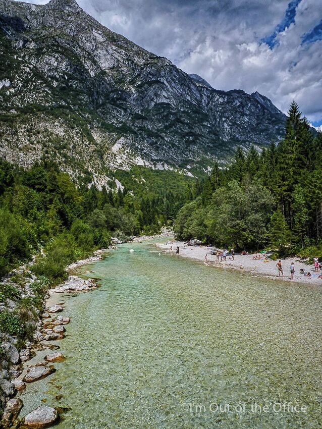A clear mountain lake surrounded by forest and rocky terrain.