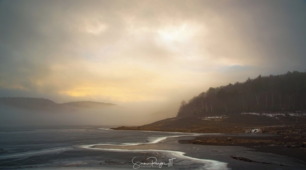 A foggy morning on the Colebrook River Lake. The sheer lines in the frozen reservoir look like the receding water on a shoreline.