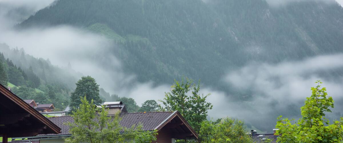 A mountain range with mist-covered peaks and a village at the base.