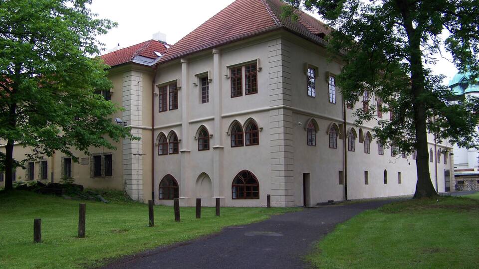 A large, historic building with a red-tiled roof and arched windows.