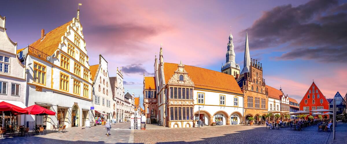 A historic European town square with traditional architecture, cobblestone streets, and a prominent church spire.