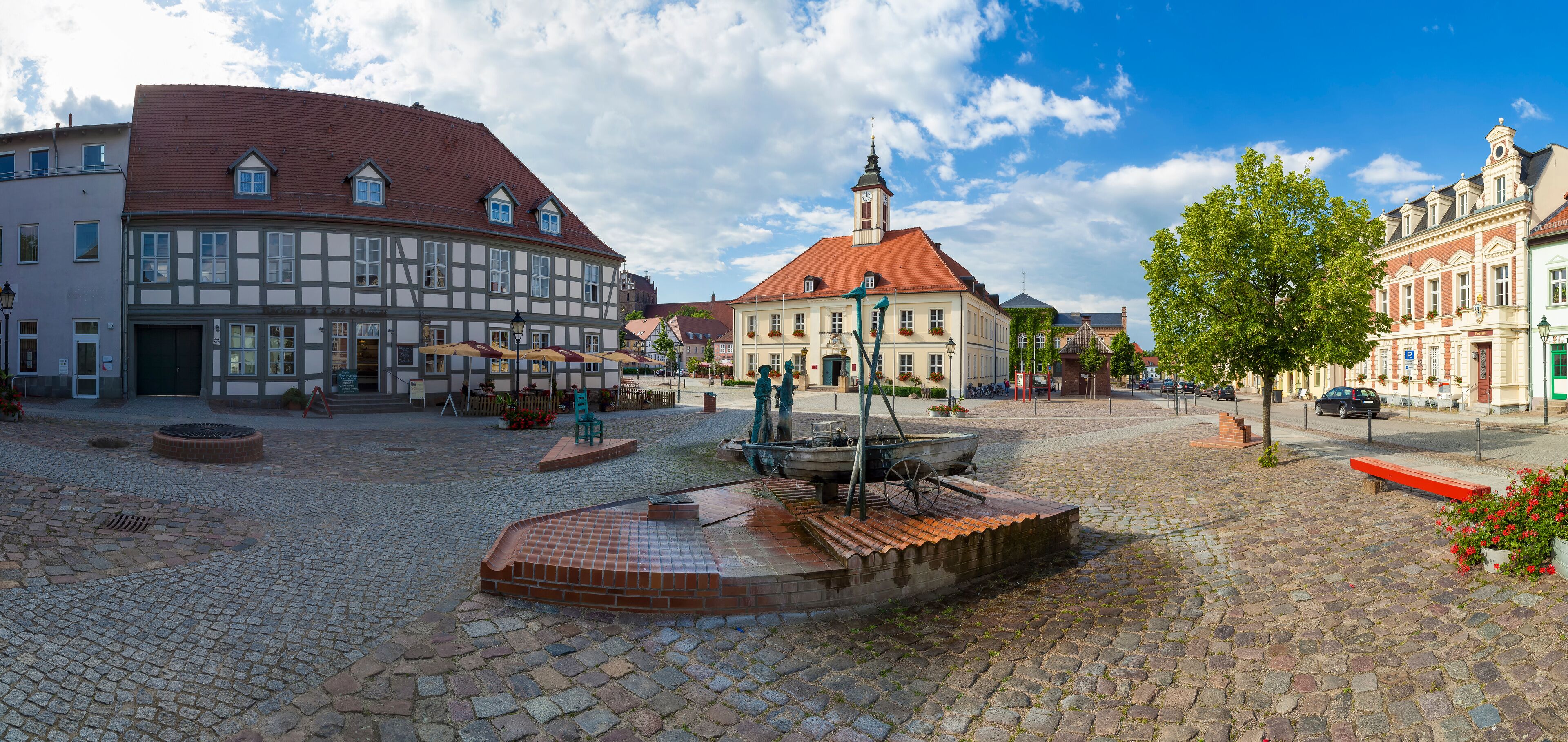 A cobblestone square with historic buildings, a fountain, and a church.