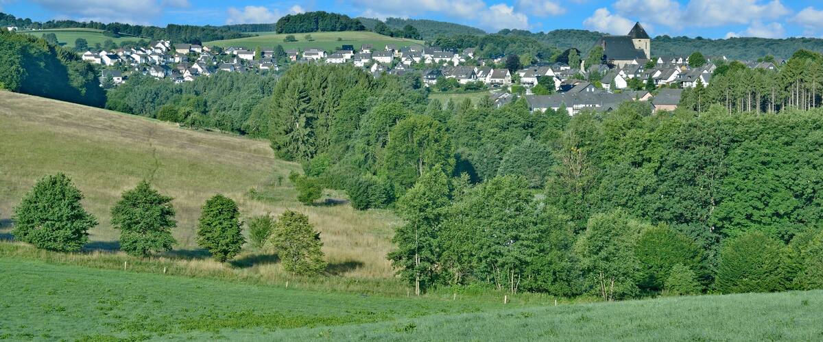 A village nestled in a valley with a prominent church on a hill.