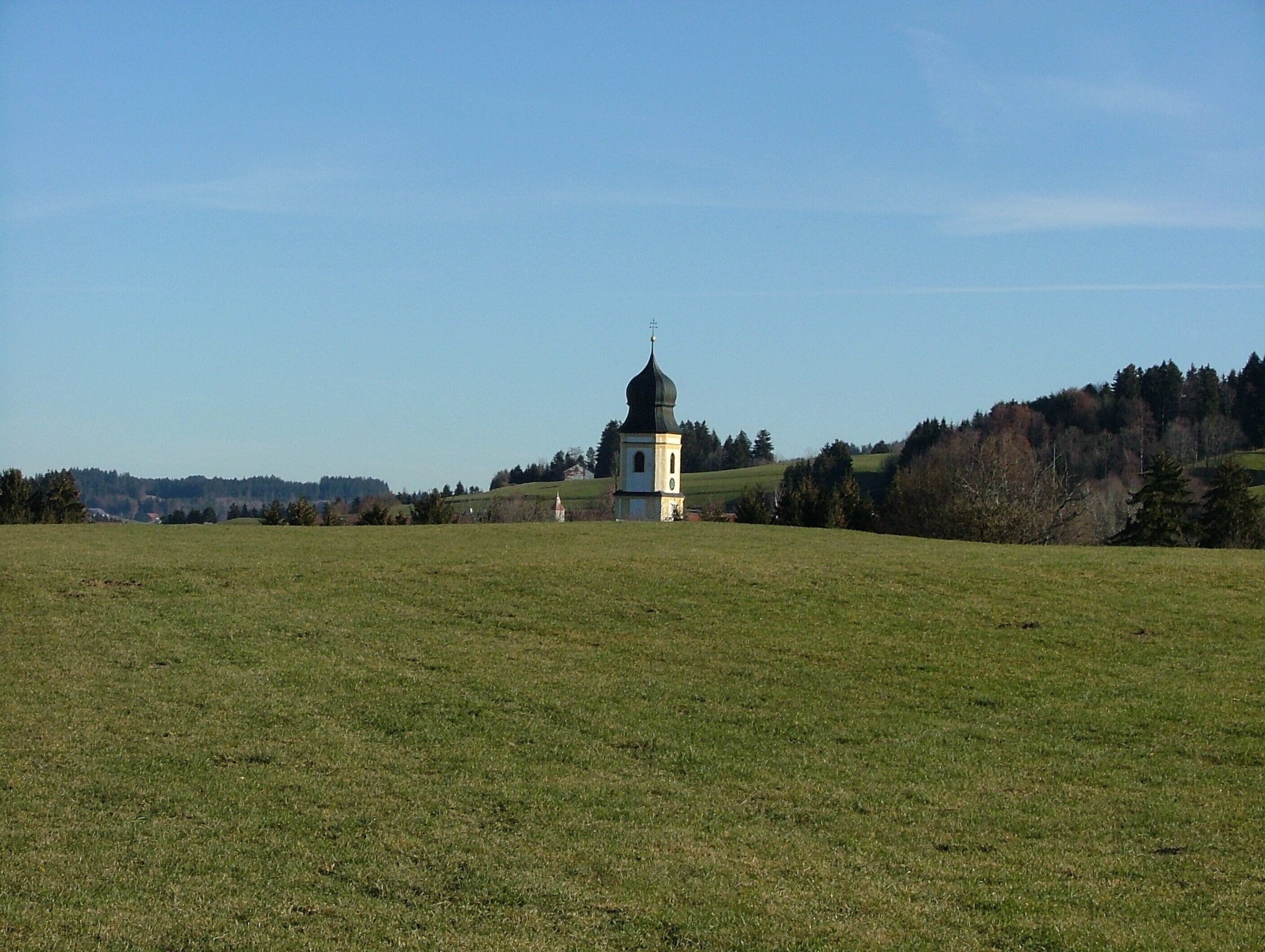A church with a green dome in a grassy field.
