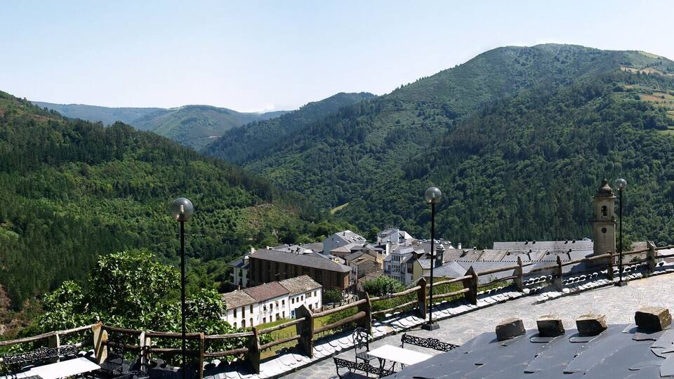 A mountainous landscape with a winding road, stone buildings, and a stone wall.