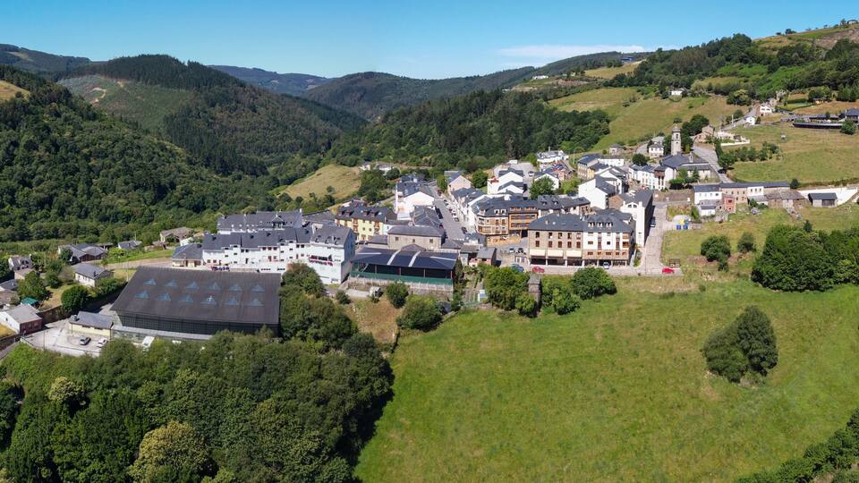 A village nestled in a valley surrounded by forested hills.