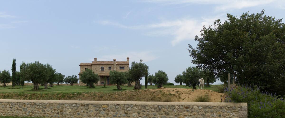 A stone wall, a stone house, and trees.