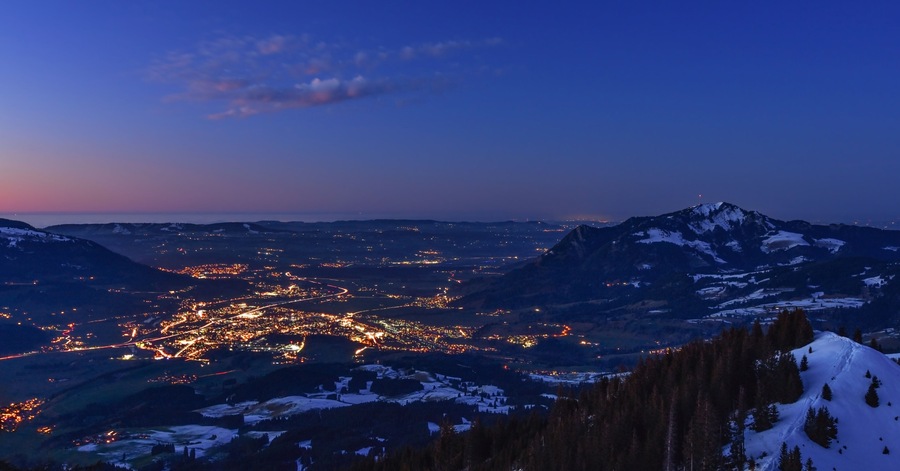 Un paisaje montañoso al atardecer con un pueblo iluminado por luces.