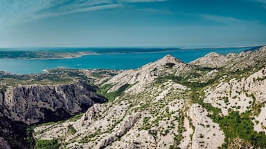 Aerial view of the rugged, sun-drenched Paklenica mountain peaks contrasting against the turquoise Adriatic Sea, Starigrad, Zadar County, Croatia.