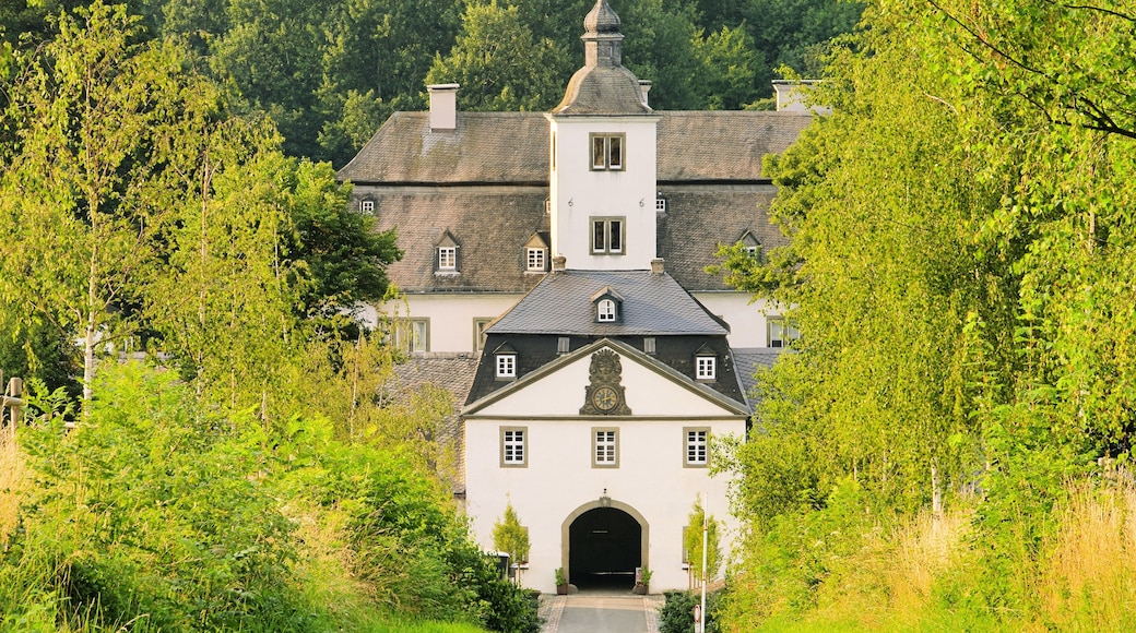 A historic building with a prominent tower, surrounded by lush greenery.
