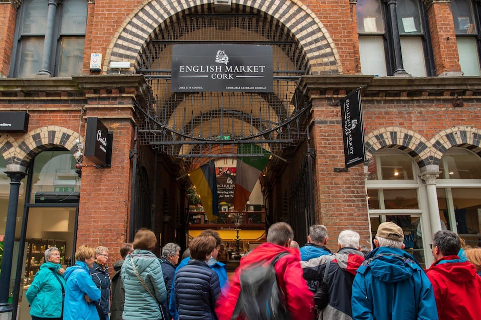 The English Market in Cork, featuring brick architecture and a crowd of people.