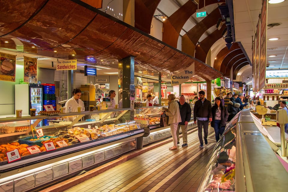 Een markt met eten, inclusief een vleeswarenbalie waar verschillende vleessoorten en kazen worden gepresenteerd.