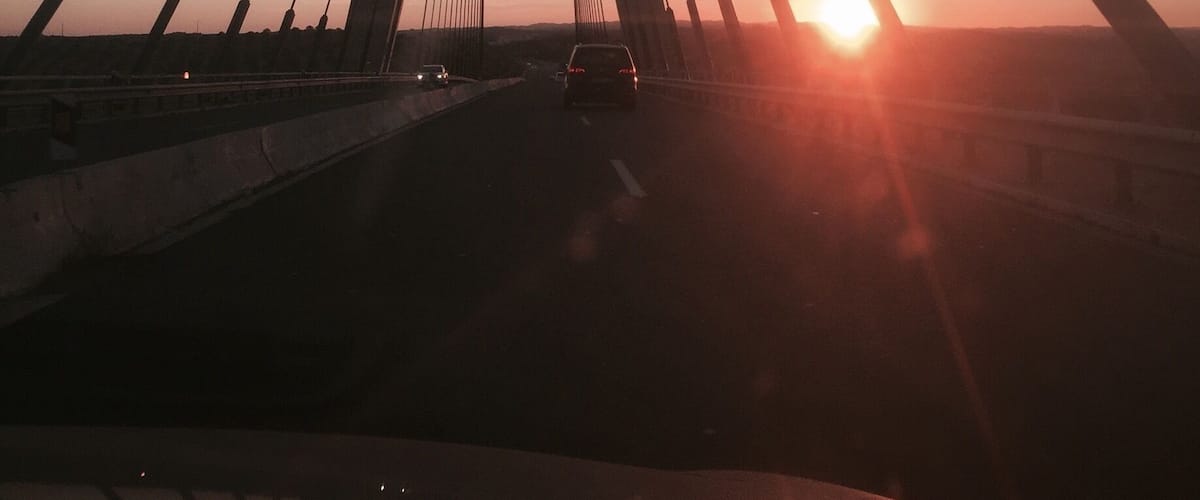A cable-stayed bridge at sunset with the sun setting behind the structure.