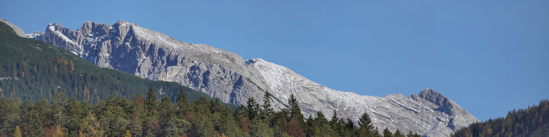 A mountain with a forested foreground and a clear blue sky.