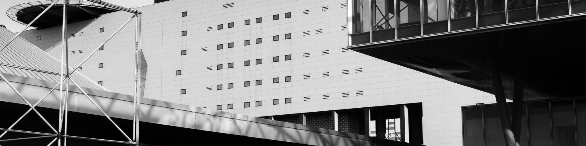 Un edificio moderno con una fachada de ventanas en forma de cuadrícula y una estructura de vidrio curvada.