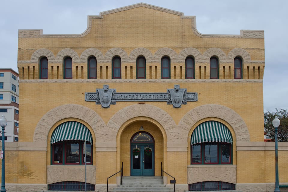 A yellow brick building with arched windows and a green awning.