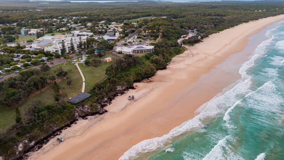 A coastal town with a sandy beach and ocean waves.