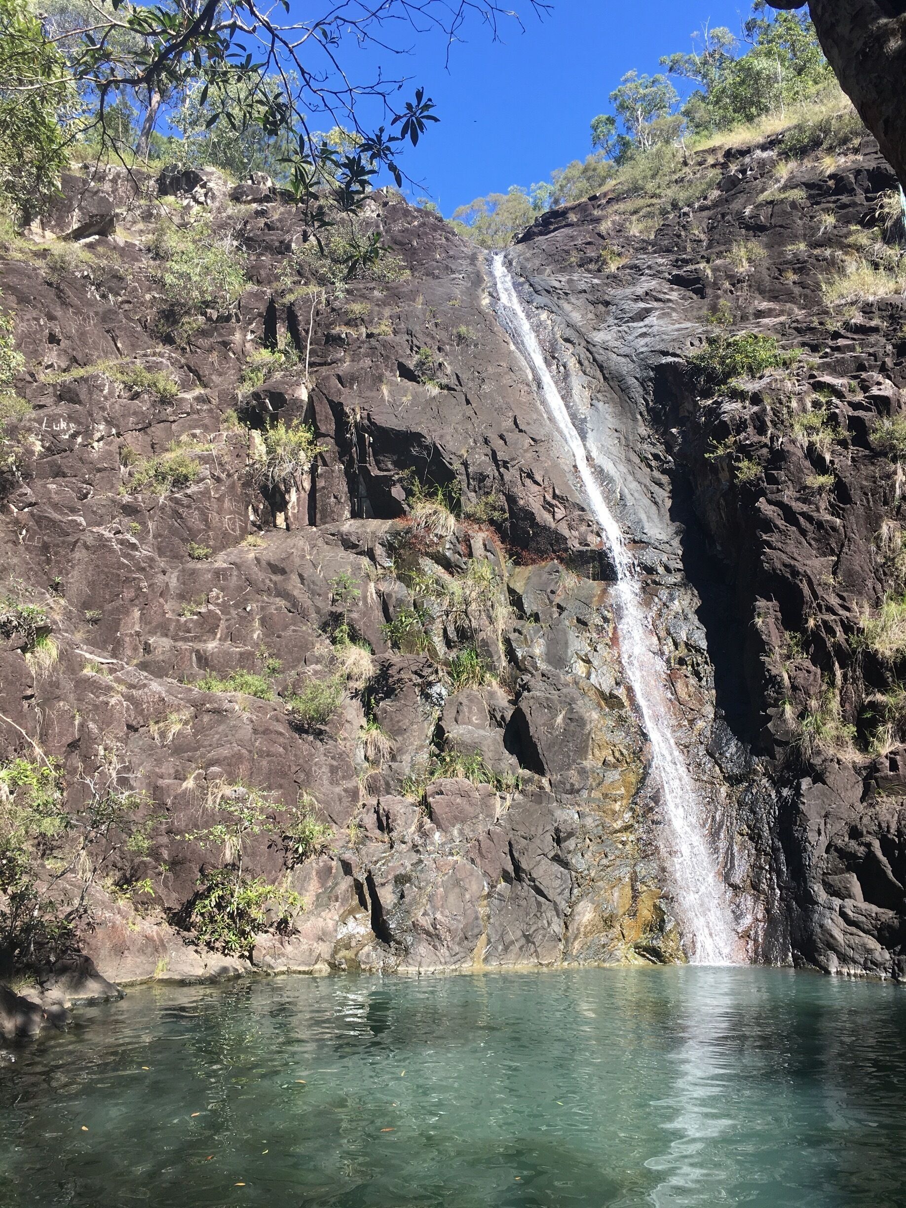 A waterfall cascading down a rocky cliff into a clear pool.
