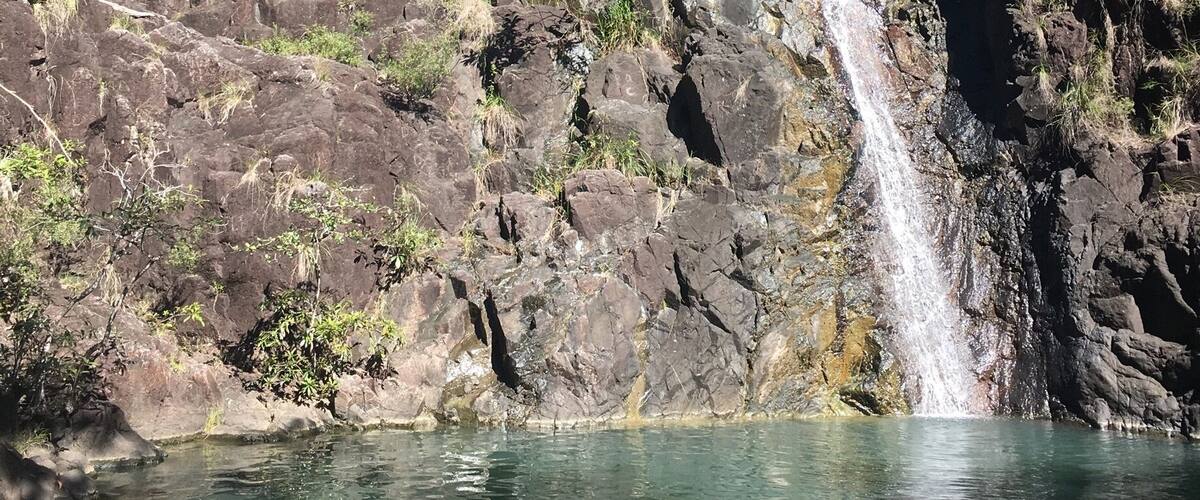 A waterfall cascading down a rocky cliff into a clear pool.