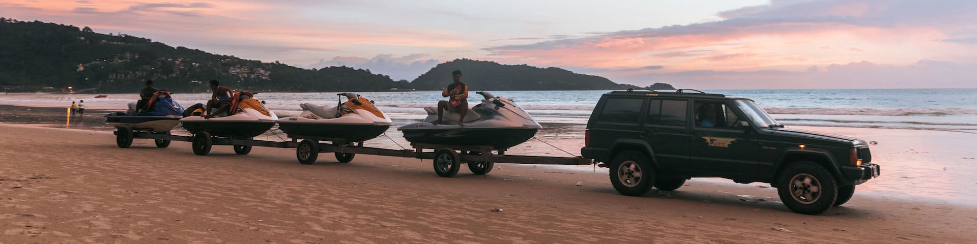 A beach with jet skis and a vehicle.
