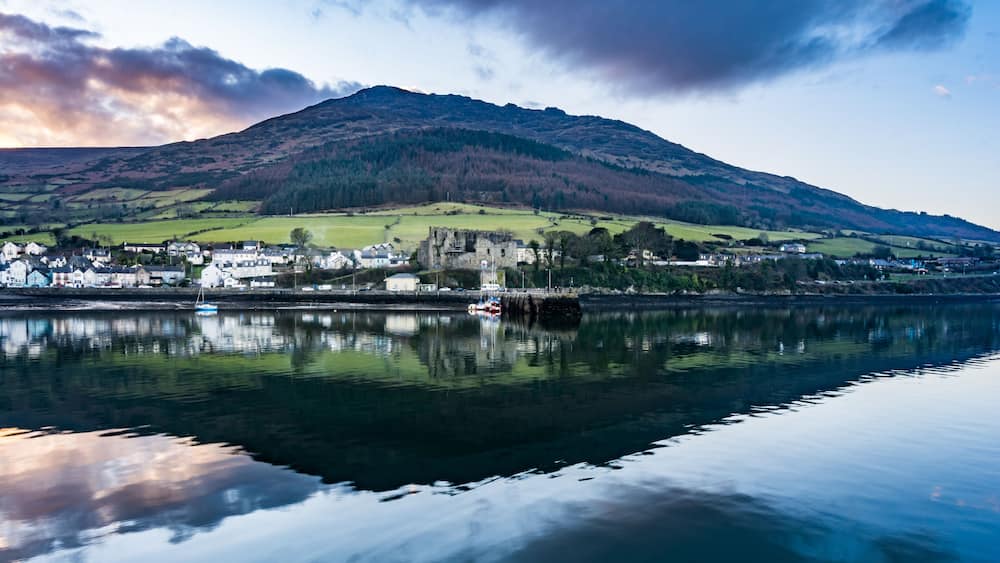 A calm lake with a town and a castle on a hill.