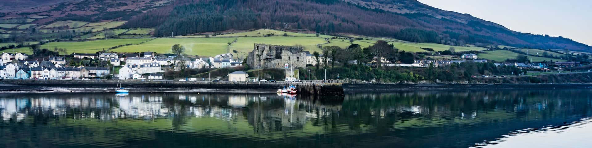 A calm lake with a town and a castle on a hill.