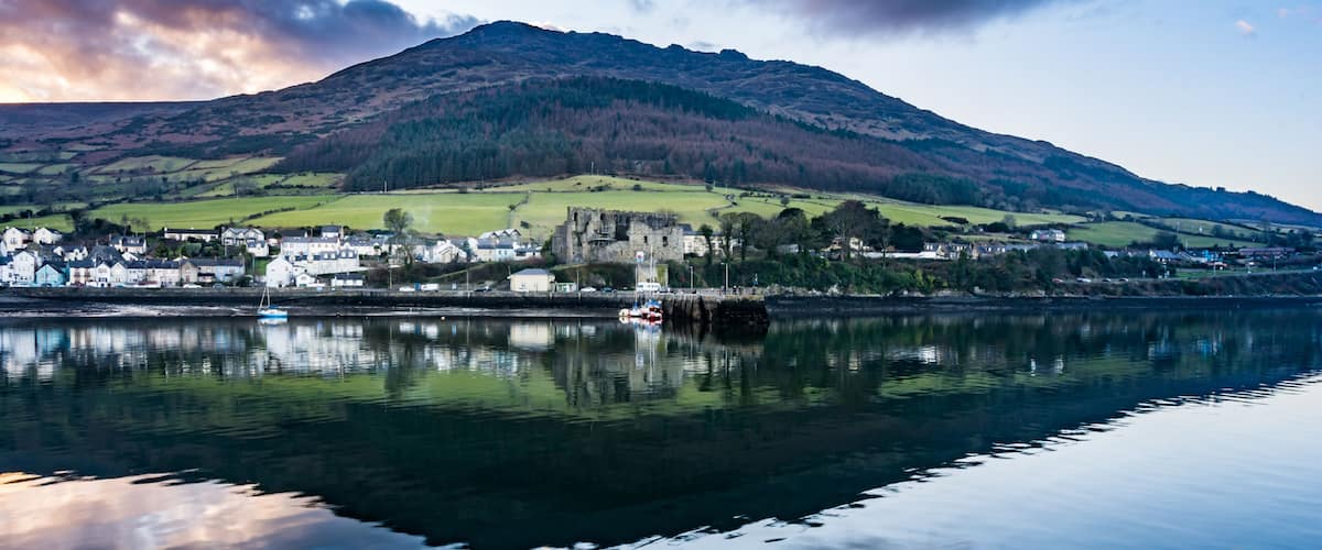 A calm lake with a town and a castle on a hill.