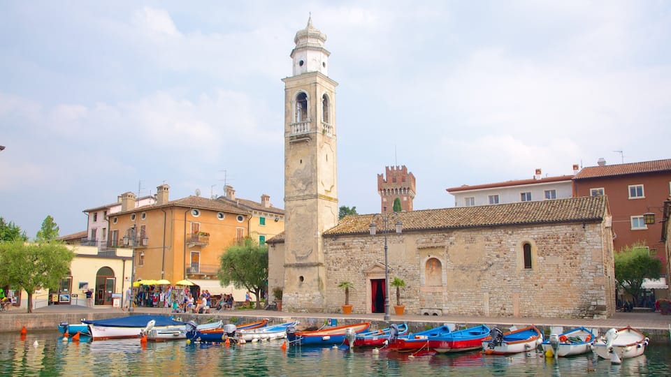 A historic town with a prominent tower, colorful boats docked at the waterfront, and traditional buildings.