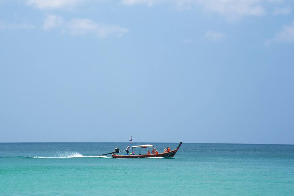 Un bateau transportant des passagers navigue sur une mer calme, sous un ciel dégagé.