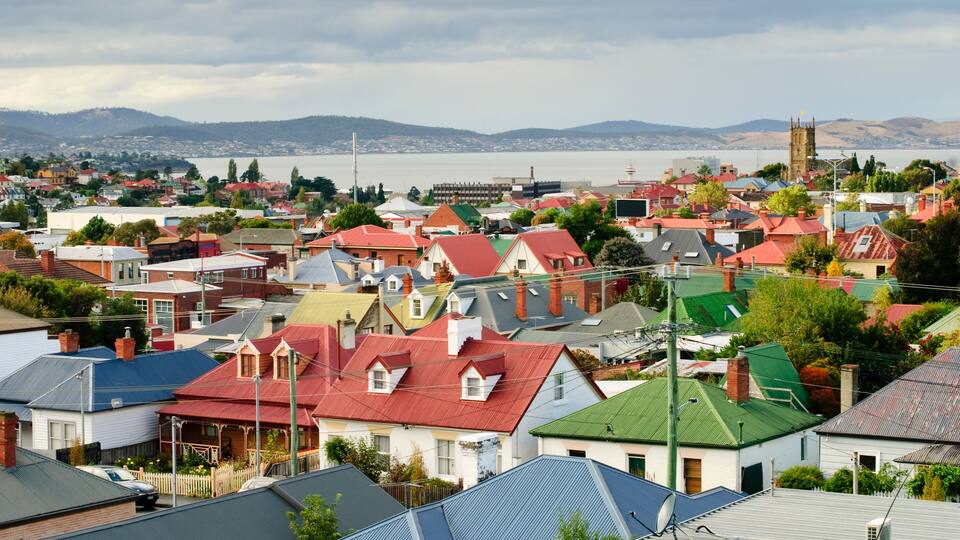A coastal town with colorful houses, a church, and a body of water in the background.