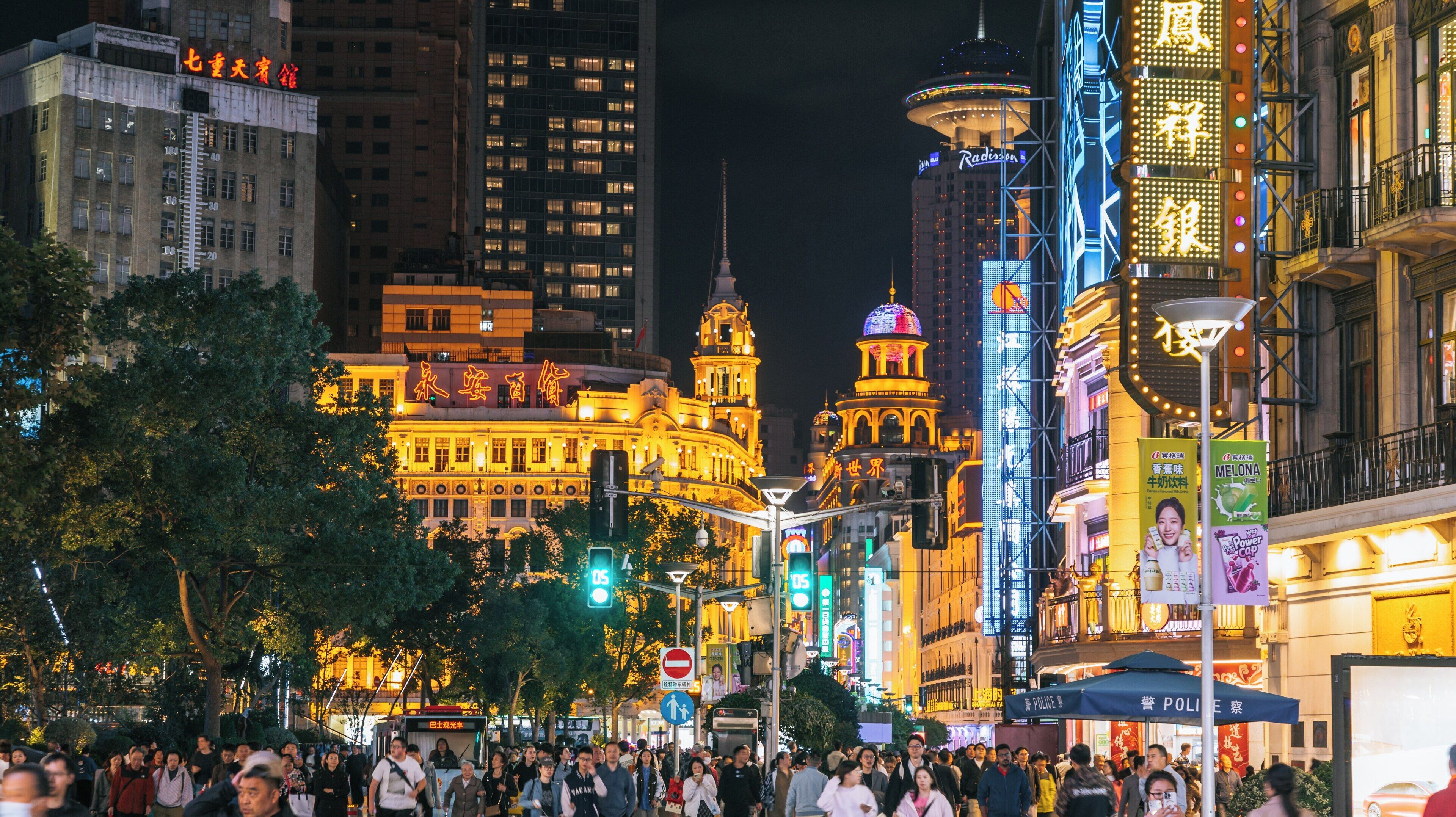 Vibrant nighttime atmosphere of Nanjing Road Shopping District in Downtown Shanghai showcasing bustling crowds and illuminated buildings