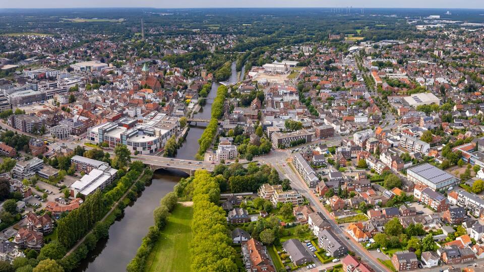 A cityscape with a river, a bridge, and surrounding greenery.