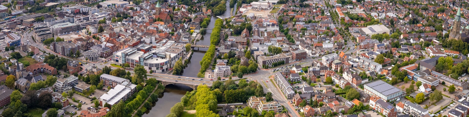 A cityscape with a river, a bridge, and surrounding greenery.