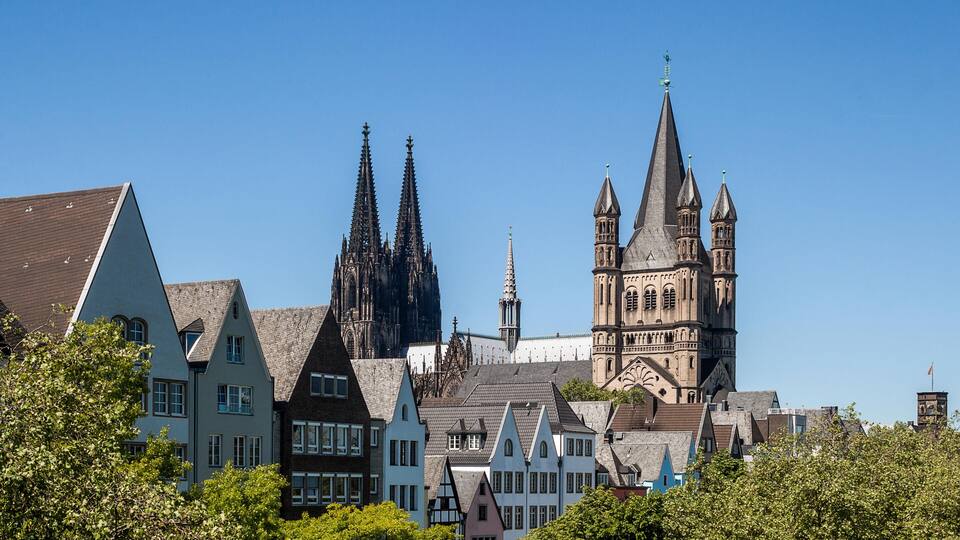 A historic town with traditional half-timbered houses, a prominent church with a tall spire, and a cathedral with two towers.