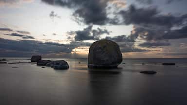 A large rock in the foreground with a sunset in the background.