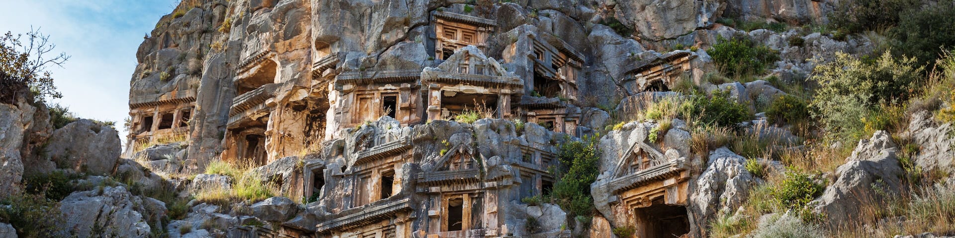 Ancient rock-cut architecture with multiple levels and chambers carved into a hillside.