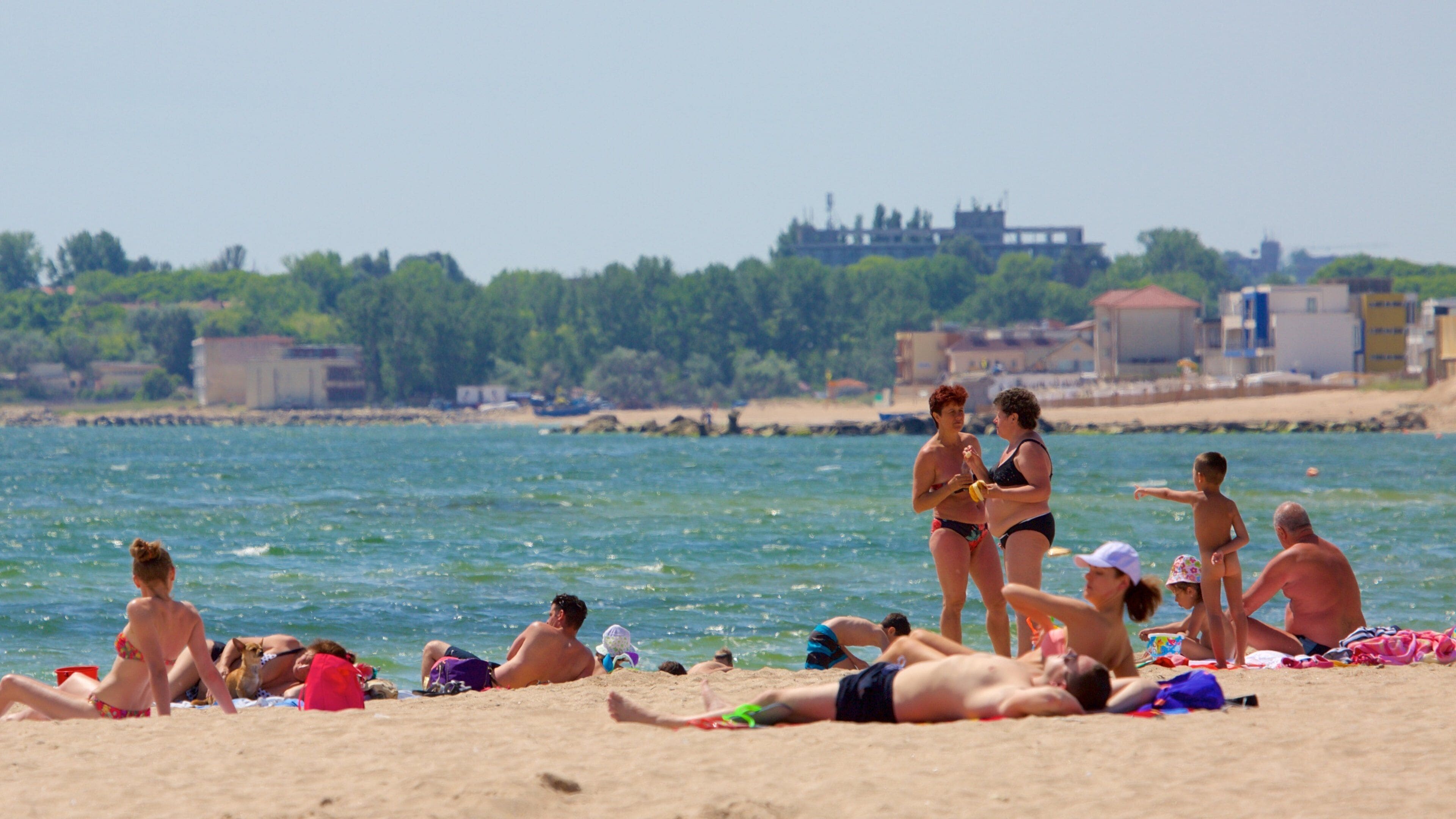 Eforie featuring a coastal town and a sandy beach as well as a large group of people