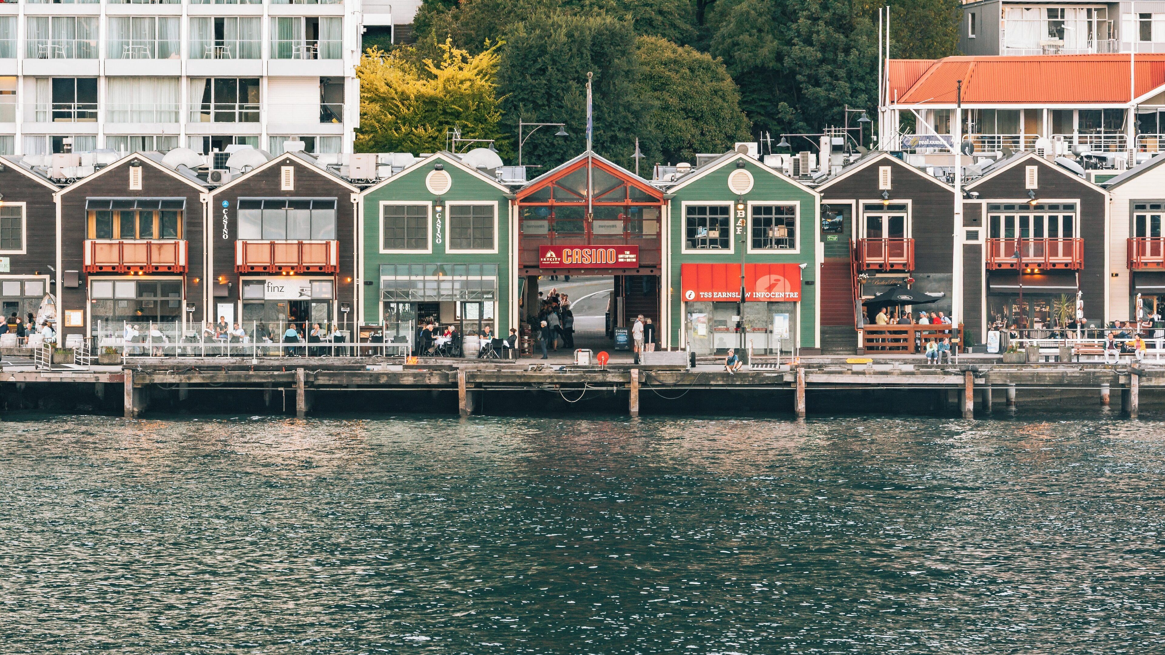 Colorful buildings along Steamer Wharf in Queenstown City Centre showcase vibrant waterfront activity and hospitality in Otago, New Zealand